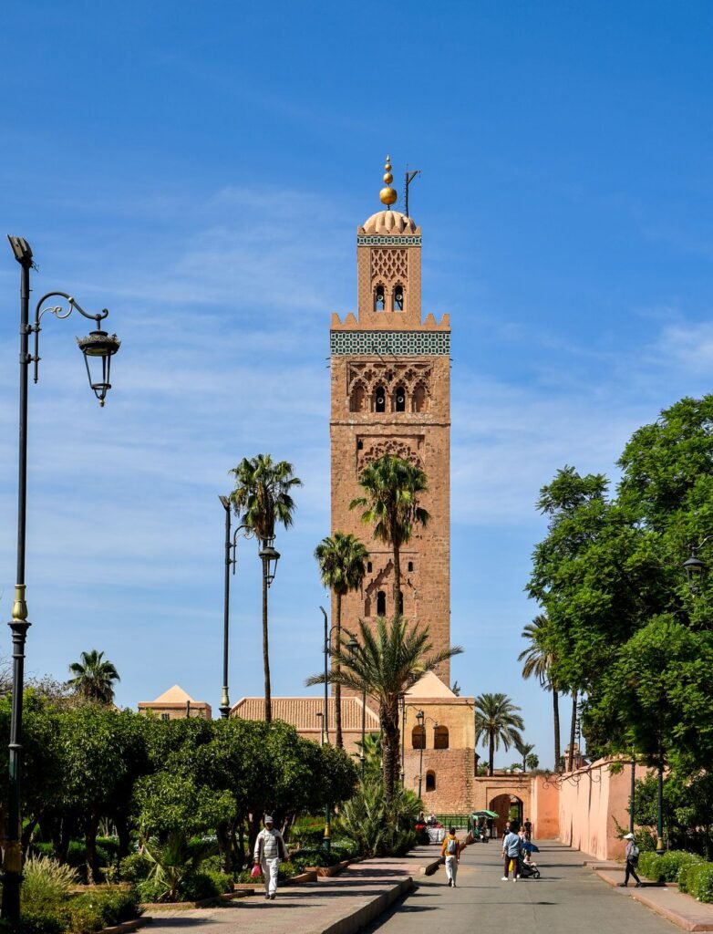 iconic Koutoubia Mosque in Marrakesh with palm trees and clear blue sky.